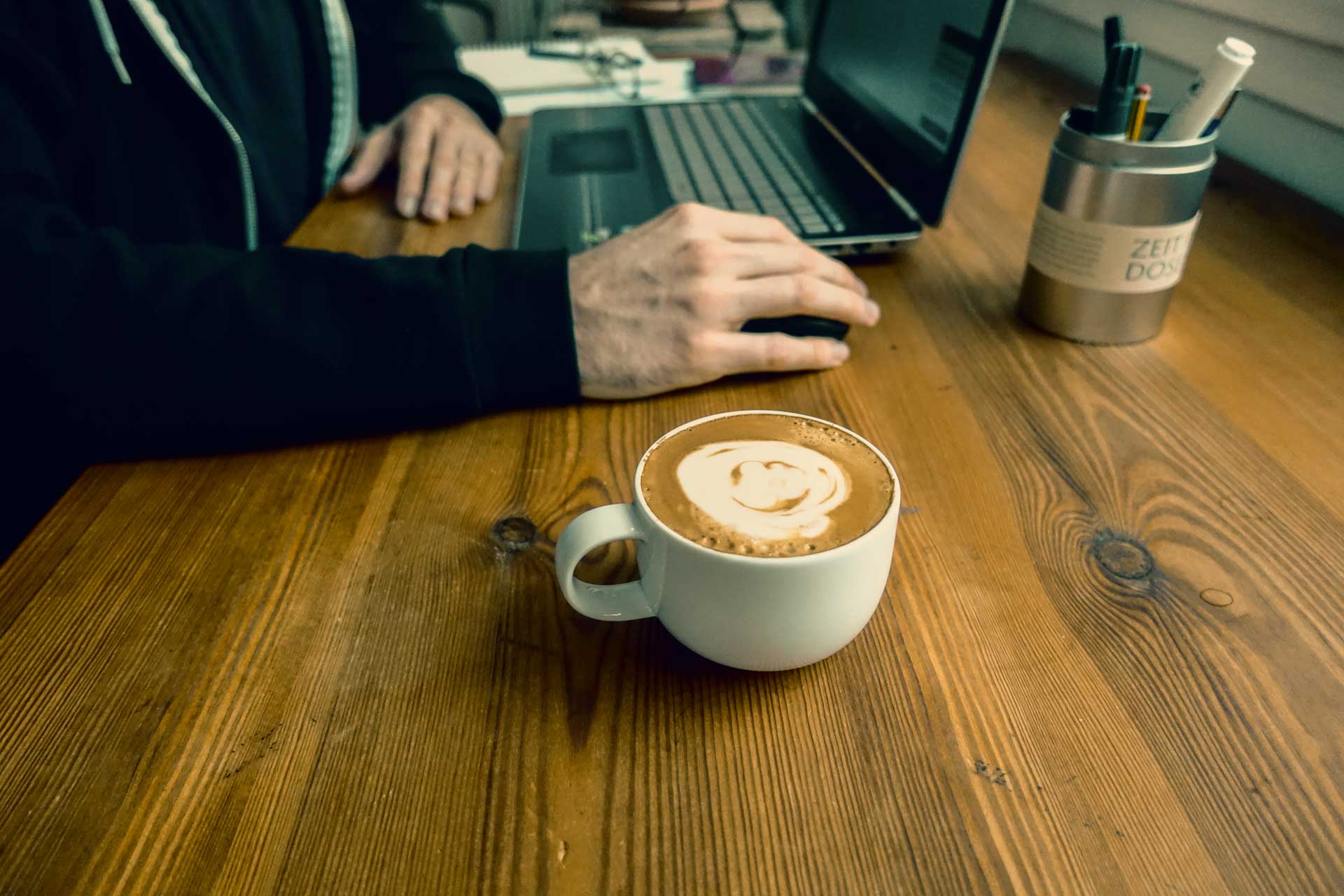 Blogger sitzt am Schreibtisch mit Kaffee und Laptop