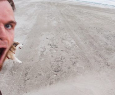 Ein Mensch und Hund haben sichtbar viel Spaß am Strand