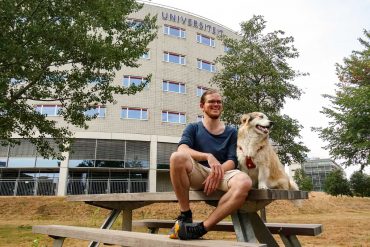 Auslandsstudium mit Hund – Ein Erfahrungsbericht Student sitzt mit Hund vor der Universität Maastricht